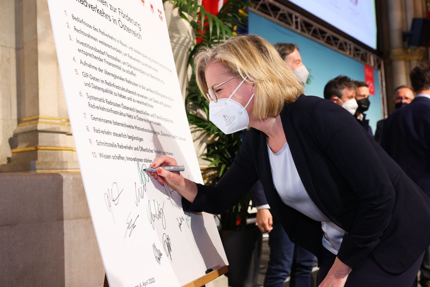 BM Leonore Gewessler unterschreibt die Übereinkunft zur Förderung des Radverkehrs. Die Übereinkunft wurde übergroß auf Karton gedruckt 