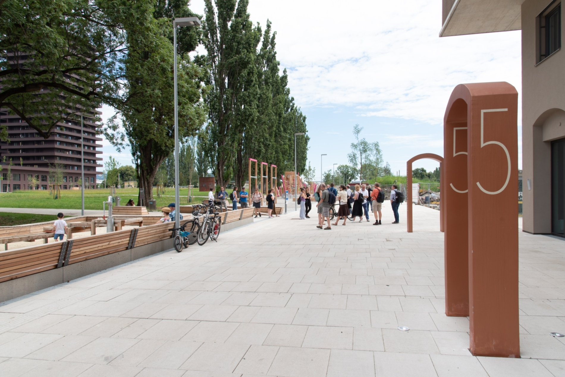 Siedlung mit breitem Geh- und Radweg. Am Rand einige Sitzbänke und Begrünung.