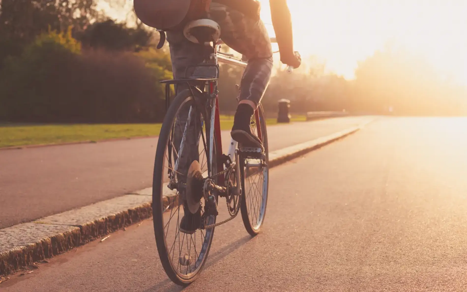 Radfahrer am Fahrrad auf einer Straße. Die Sonne scheint.