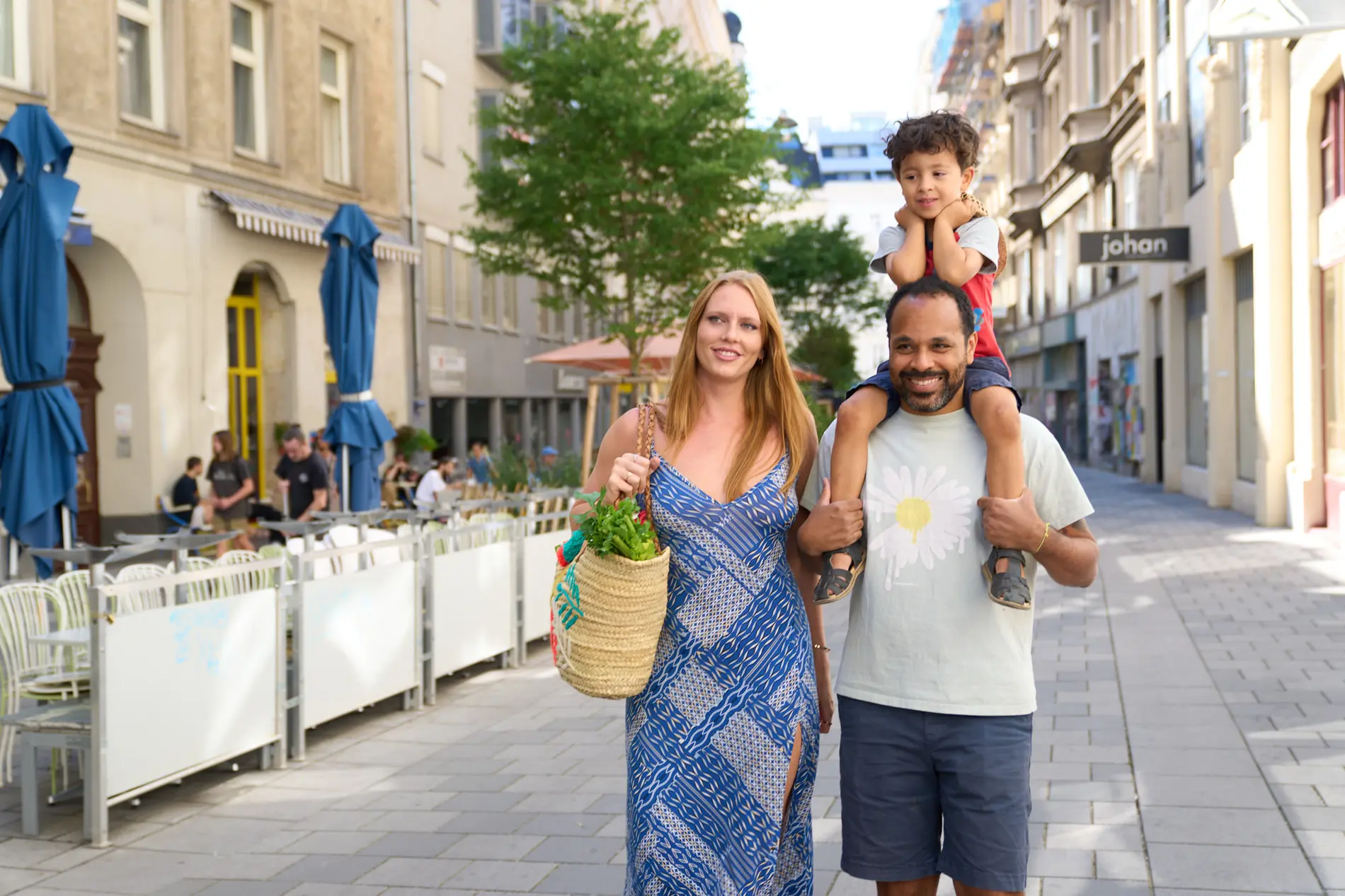 Familie mit Kleinkind zu Fuß unterwegs. Das Kind sitzt auf den Schultern des Vaters