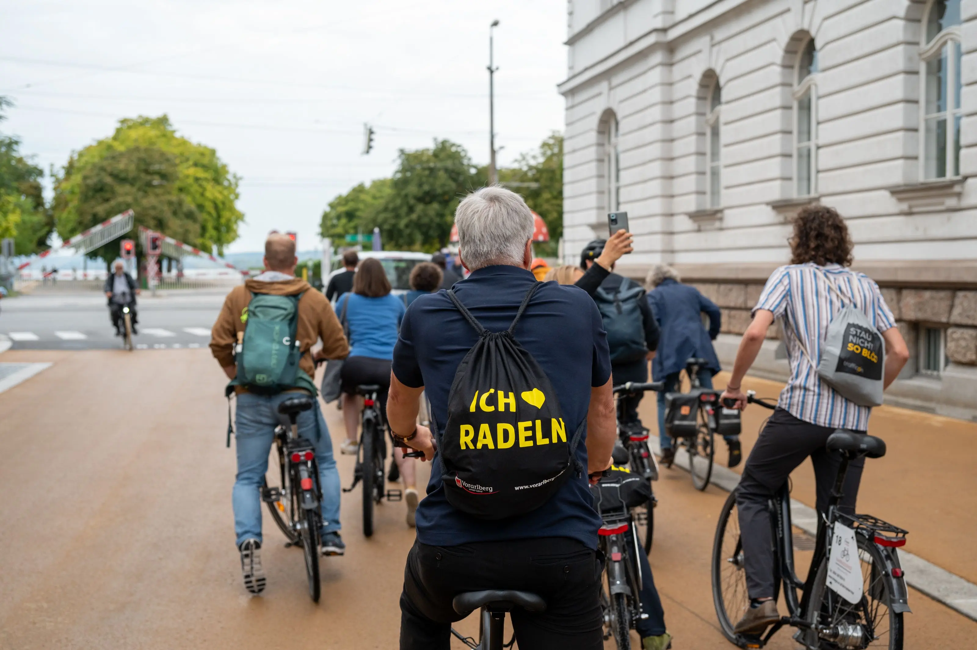 Radler:innen von hinten. Sie befinden sich auf einem breiten Radweg.